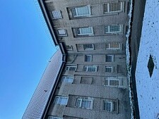 Gebäude mit vergitterten Fenstern, es liegt Schnee davor. Oben im Bild sieht man blauen Himmel