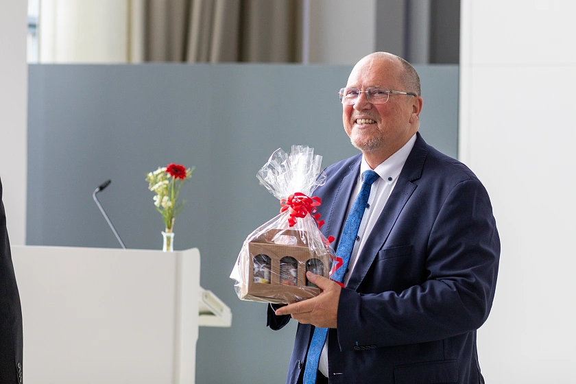 Prof. Dr. Arloth lächelt und hält ein Paket mit Saucen in den Händen