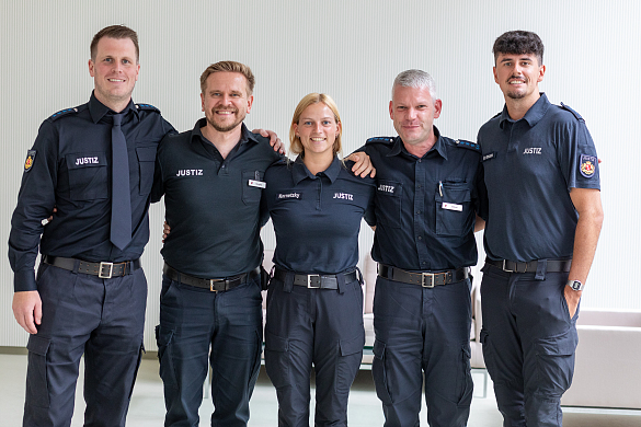 Fünf Mitarbeiterinnen und Mitarbeiter in Uniform lächeln in die Kamera