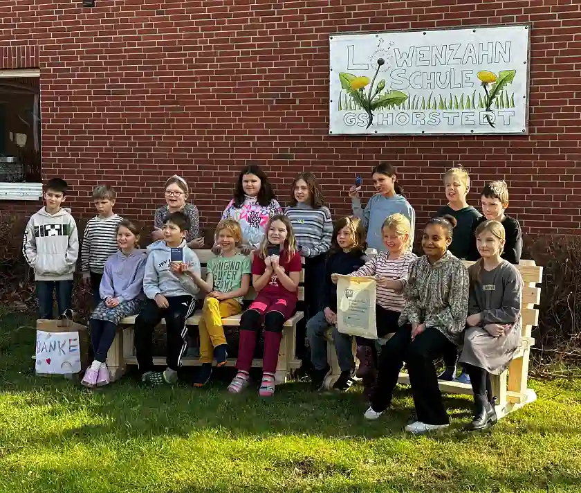 Gruppenfoto von Kindern, die auf zwei Holzbänken sitzen