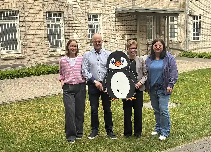 Maskottchen Pico im Innenhof der JVA mit der Senatorin, dem Justizvollzugsabteilungsleiter, der JVA-Familienbeauftragten und der Geschäftsführerin von hoppenbank e.V.