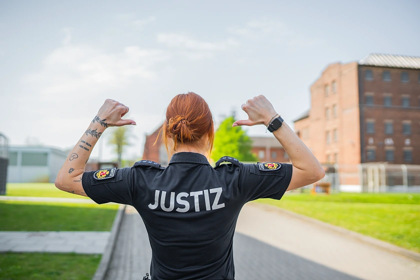 JVA-Mitarbeiterin, die auf den Schriftzug Ihres Shirts zeigt: Justiz