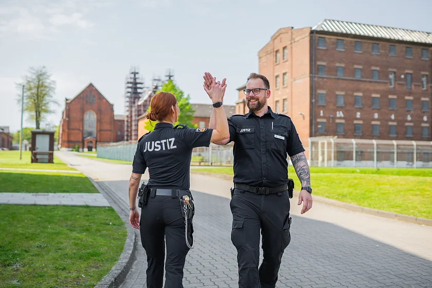 eine Justizvollzugsbeamtin und ein Justizvollzugsbeamter auf dem Außengelände der JVA
