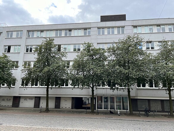 Bürogebäude mit fünf Stockwerken, davor stehen Bäume und Fahrradständer