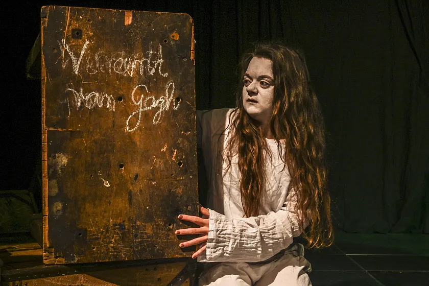 Schauspielerin in weißem Gewand mit blassem Gesicht und sehr dunklen Augen