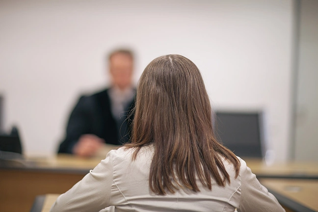 eine Frau sitzt vor einem Richter in einem Gerichtssaal